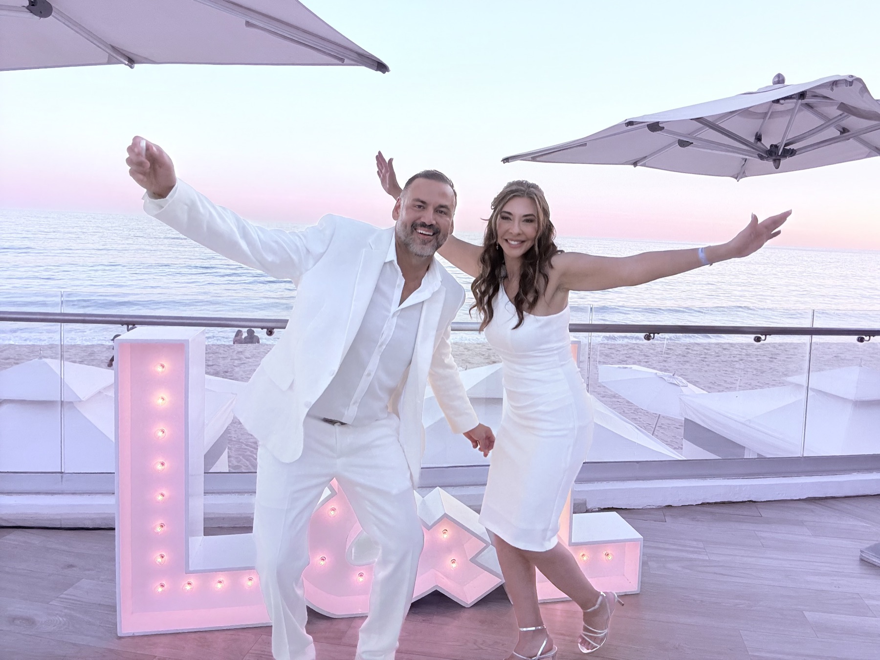 Lorenzo and Lisa, arms wide, on the deck at sunset