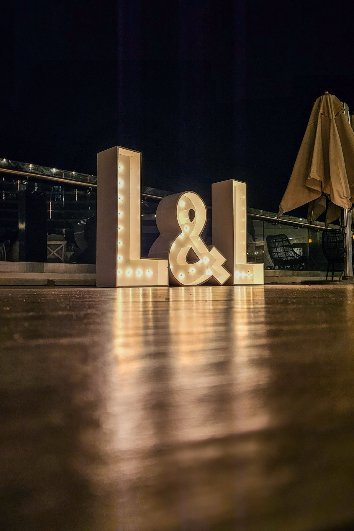 The L&L marquee letters glowing on the rooftop at night