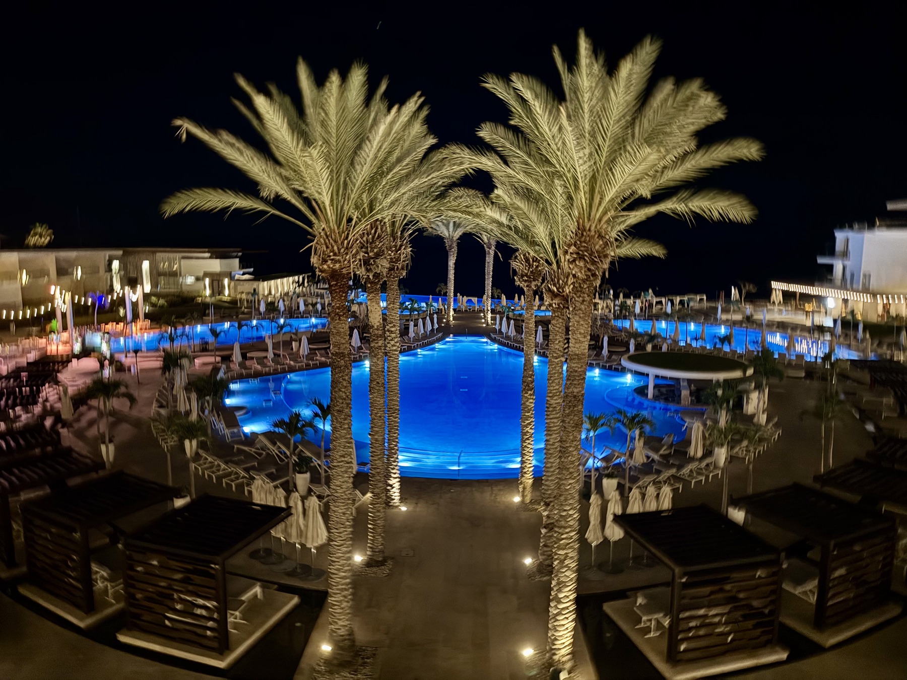 The Le Blanc pool glowing blue under the palms at night