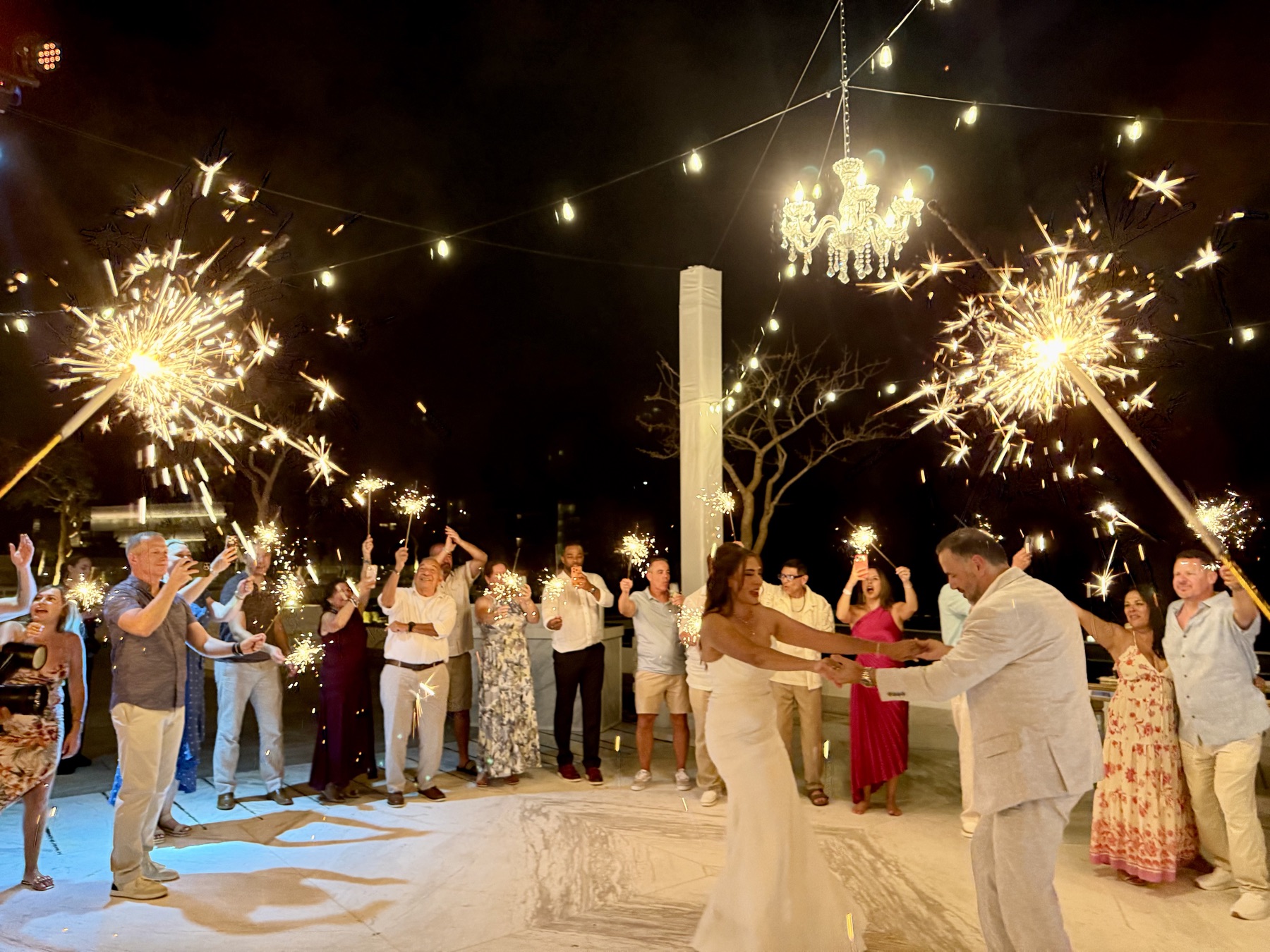 Dancing in a circle of guests waving sparklers under the chandelier