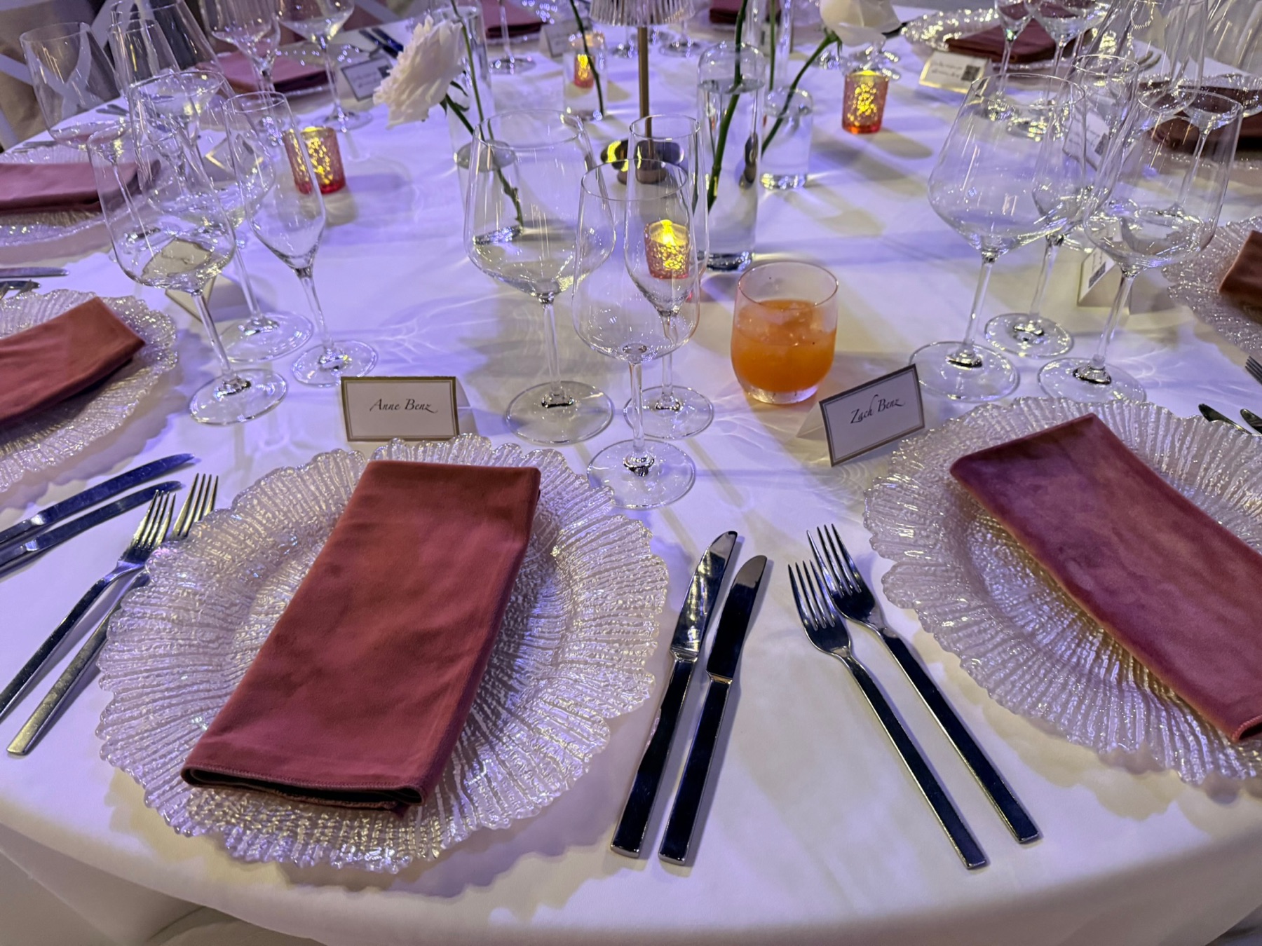 Rose napkins and glass chargers on the reception table